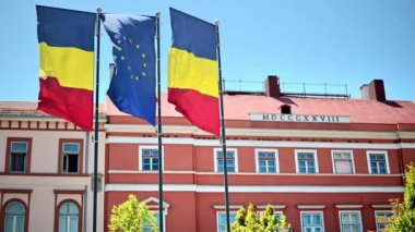 Two national flags and one of the European Union in Cluj centre, Romania. Classic building on the background