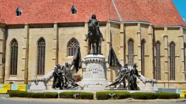 CLUJ, ROMANIA - JULY, 2022: Street scape of Cluj centre, Romania. Central square with Saint Michael Church and statue of Matthias Corvinus in front of it