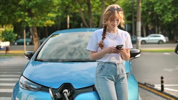 Young Blonde Woman Using Smartphone Car Charging Station Charging Electric — Stockvideo