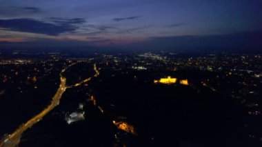 Aerial drone view of main central square in Brasov at night, Romania. Old city centre with County Museum of History, Black church, buildings, nightlights, people