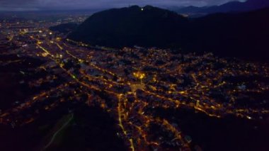 Aerial drone view of the Saint Nicholas Church in Brasov at night, Romania. Medieval church with multiple buildings and roads with nightlights