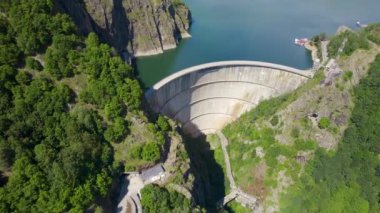 Romanya 'da doğanın insansız hava aracı görüntüsü. Vidraru barajı ve gölü olan Karpat dağlarındaki vadi, yemyeşil ormanlı yamaçlar.