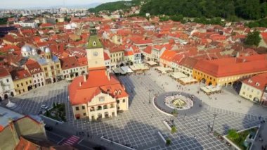 Aerial drone view of main central square in Brasov at night, Romania. Old city centre with County Museum of History, Black church, buildings, nightlights, people