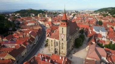 Aerial drone view of main central square in Brasov at night, Romania. Old city centre with County Museum of History, Black church, buildings, nightlights, people
