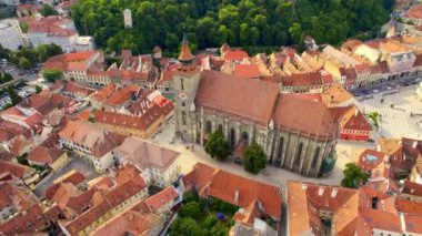 Aerial drone view of main central square in Brasov at night, Romania. Old city centre with County Museum of History, Black church, buildings, nightlights, people