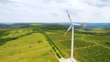 A working windmill in a field. Cloody weather, a lot of greenery around it