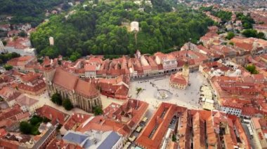 Aerial drone view of main central square in Brasov at night, Romania. Old city centre with County Museum of History, Black church, buildings, nightlights, people