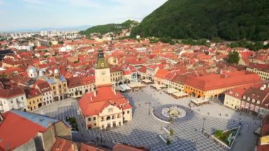 Aerial drone view of main central square in Brasov at night, Romania. Old city centre with County Museum of History, Black church, buildings, nightlights, people