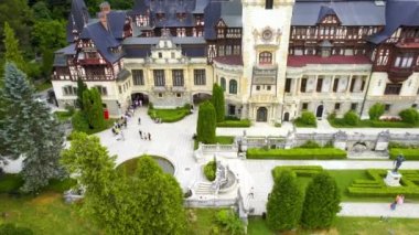 Romanya 'daki Peles Kalesi' nin insansız hava aracı görüntüsü. Karpatlar 'da bahçeleri ve turistleri olan bir kale. Etrafında bereketli ormanlar var.