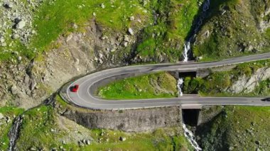 Aerial drone view of nature in Romania. Transfagarasan route in Carpathian mountains with moving cars, rocky slopes with greenery