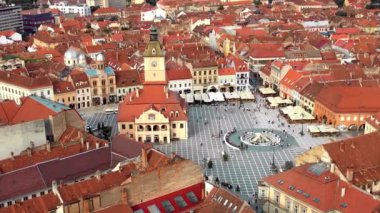 Aerial drone view of main central square in Brasov at night, Romania. Old city centre with County Museum of History, Black church, buildings, nightlights, people