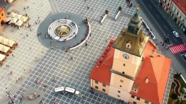 Aerial drone view of main central square in Brasov at night, Romania. Old city centre with County Museum of History, Black church, buildings, nightlights, people