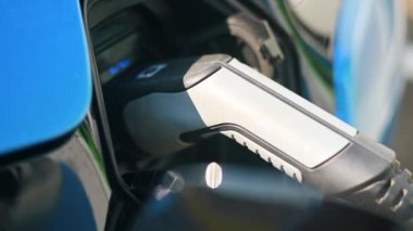 Close view of a charger plugged into an electric car at a charging station