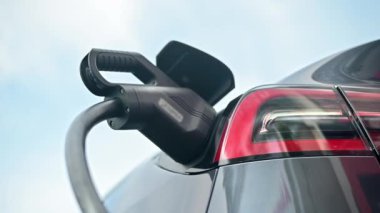 Close view of a charger plugged into an electric car at a charging station