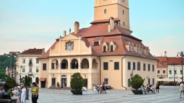 BRASOV, ROMANIA - JULY, 2022: View of the old city centre. Council Square with County Museum of History and walking people, restaurants and old buildings