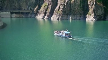 CURTEA DE ARGES, ROMANIA - JULY, 2022: View of nature in Romania. Valley in Carpathian mountains with Vidraru dam and lake, floating boat with people