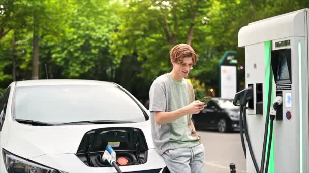 Young Man Using Smartphone Car Charging Station Charging Electric Car — Stok video