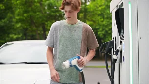 Young Man Takes Charger Car Charging Station Inserts Electric Car — Vídeo de Stock