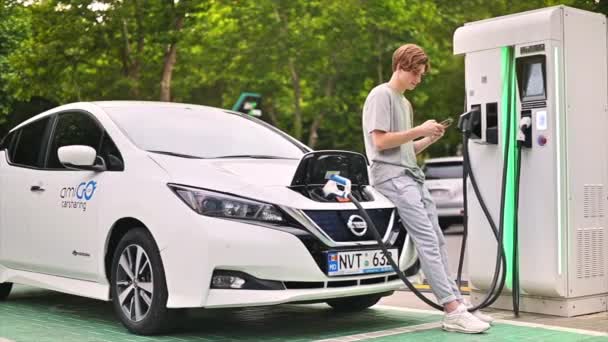 Young Man Using Smartphone Car Charging Station Charging Electric Car — Videoclip de stoc
