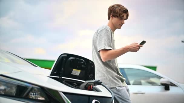 Young Man Using Smartphone Car Charging Station Charging Electric Car — Video