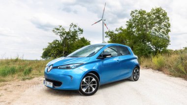 BACAU, ROMANIA - JULY, 2022: Parked electric Renault ZOE on the road, windmill on the background, greenery