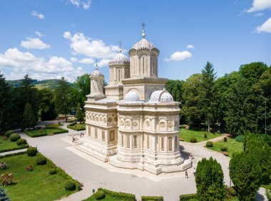 CURTEA DE ARGES, ROMANIA - JULY, 2022: Aerial drone view of the Curtea de Arges Monastery. Main cathedral facade, greenery and people
