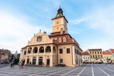 BRASOV, ROMANIA - JULY, 2022: View of the old city centre. Council Square with County Museum of History and walking people, restaurants and old buildings