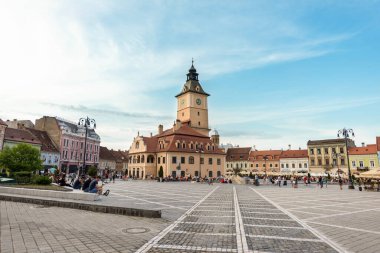 BRASOV, ROMANIA - JULY, 2022: View of the old city centre. Council Square with County Museum of History and walking people, restaurants and old buildings