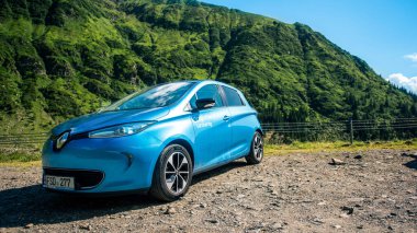 TRANSFAGARAS, ROMANIA - JULY, 2022: Parked electric Renault ZOE at Transfagarasan route. Mountains slopes covered with greenery on the background