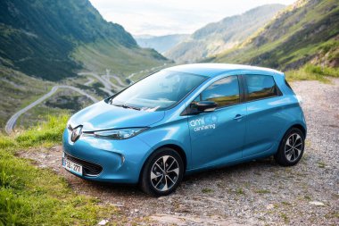 TRANSFAGARAS, ROMANIA - JULY, 2022: Parked electric Renault ZOE at Transfagarasan route. Mountains slopes covered with greenery on the background