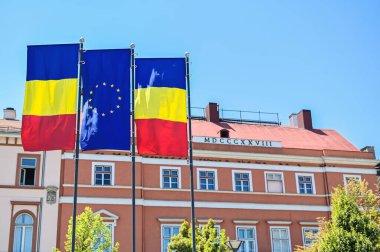 Two national flags and one of the European Union in Cluj centre, Romania. Classic building on the background
