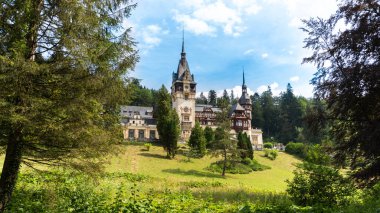 View of The Peles Castle in Romania. Castle with gardens in Carpathians, lush forest around it
