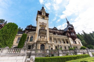 Wide view of The Peles Castle in Romania. Castle with gardens in Carpathians, lush forest around it