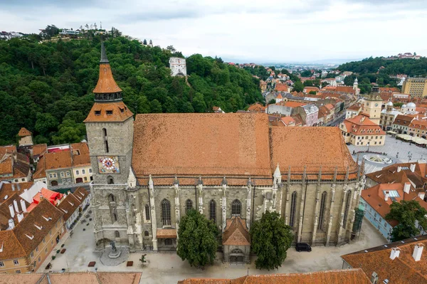 Romanya 'nın eski Brasov merkezindeki Kara Kilise' nin insansız hava aracı görüntüsü. Çevresindeki eski binalar, yeşillikli tepeler.