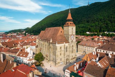 Romanya 'nın eski Brasov merkezindeki Kara Kilise' nin insansız hava aracı görüntüsü. Çevresindeki eski binalar, yeşillikli tepeler.