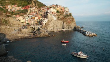 View of Manarola at sunset, located on the Ligurian sea coast, Italy. Rows of residential buildings, greenery