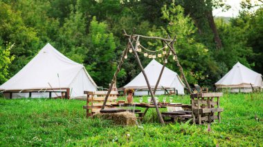Table with food and drinks at glamping, Greenery around, tents on the background