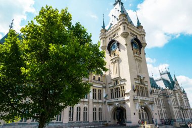 IASI, ROMANIA - AUGUST, 2022: View of the Palace of Culture in downtown. Square with Stephen the Great statue, people and greenery in front of it