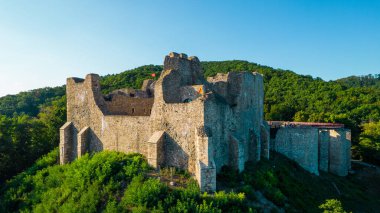 Aerial drone view of the Neamt Citadel in Targu Neamt, Romania. Fortress with tourists on the top of a hill, surrounded by lush forest
