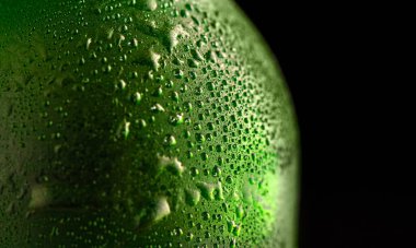Close view of the green bottle with condensate, black background