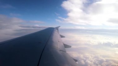 Uçak kanadı ve mavi gökyüzü, uçuş sırasında beyaz bulutlar...