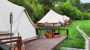 Tents with wooden chairs at glamping, Lush forest around