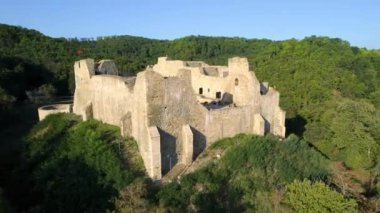 Aerial drone view of the Neamt Citadel in Targu Neamt, Romania. Fortress with tourists on the top of a hill, surrounded by lush forest