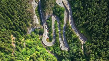 Aerial drone view of nature in Romania. Carpathian mountains, serpentine road with cars in the valley, rocky cliffs covered with lush forest