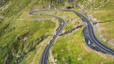 Aerial drone view of nature in Romania. Transfagarasan route in Carpathian mountains with moving cars, rocky slopes with greenery