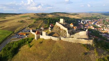 Aerial drone view of Rupea Fortress at sunset, Romania. Citadel located on a cliff, tourists, town, greenery
