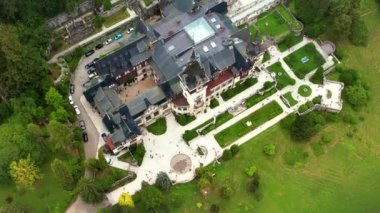 Romanya 'daki Peles Kalesi' nin insansız hava aracı görüntüsü. Karpatlar 'da bahçeleri ve turistleri olan bir kale. Etrafında bereketli ormanlar var.