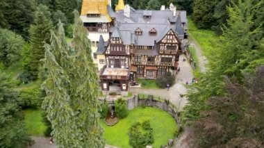 SINAIA, ROMANIA - AĞUSTOS, 2022: Romanya 'daki Pelisor Kalesi' nin insansız hava aracı görüntüsü. Karpatlar 'da bahçe ve turistlerle dolu bir kale, etrafındaki yemyeşil ormanlar.
