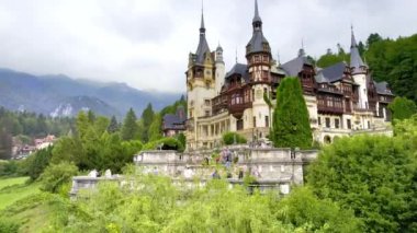 SINAIA, ROMANIA - 2022 AĞUSTOS: Karpatlar 'da bahçeleri ve turistleri olan bir kale. Etrafında bereketli ormanlar var.