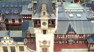 SINAIA, ROMANIA - AĞUSTOS, 2022: Romanya 'daki Peles Kalesi' nin insansız hava aracı görüntüsü. Karpatlar 'da bahçe ve turistlerle dolu bir kale cephesi, etrafındaki yemyeşil ormanlar.